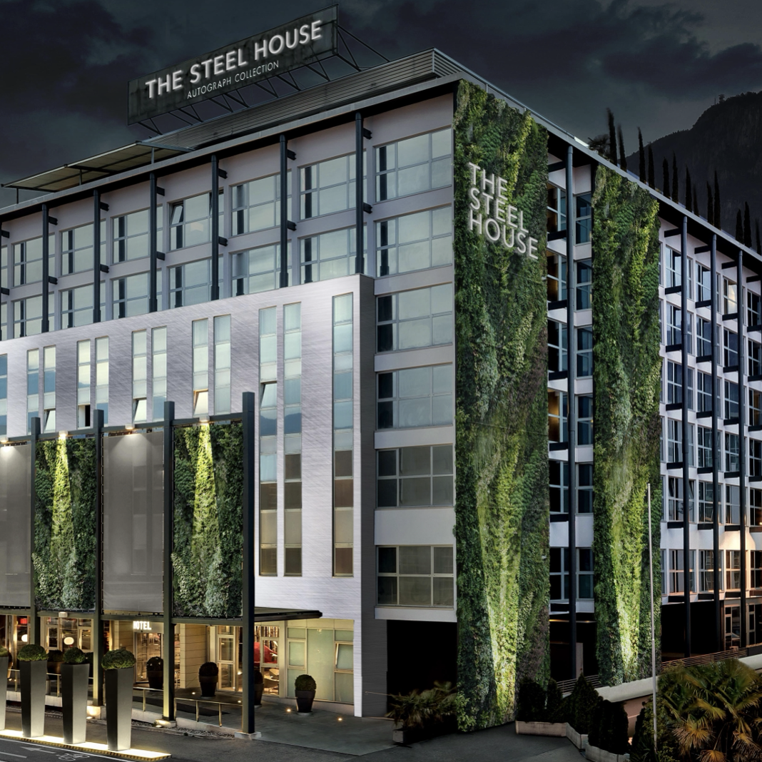 The Steel House conference hotel with green planted facade at dusk - Bolzano, Italy